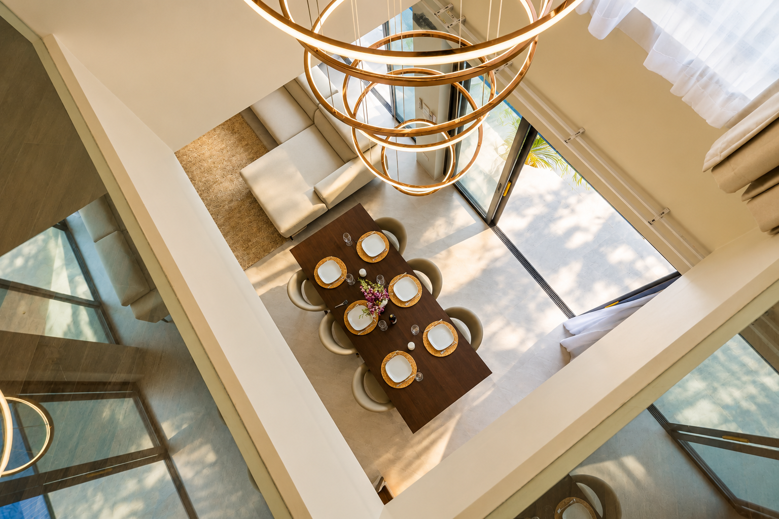 View down from the upper floor over the dining table, sofa and circular pendant lights