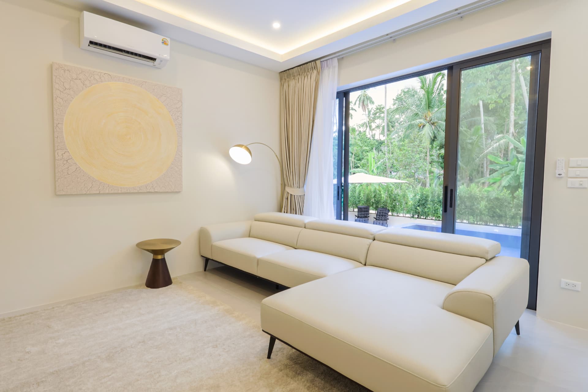 Living room with a large cream corner sofa and sliding doors opening to the pool and garden