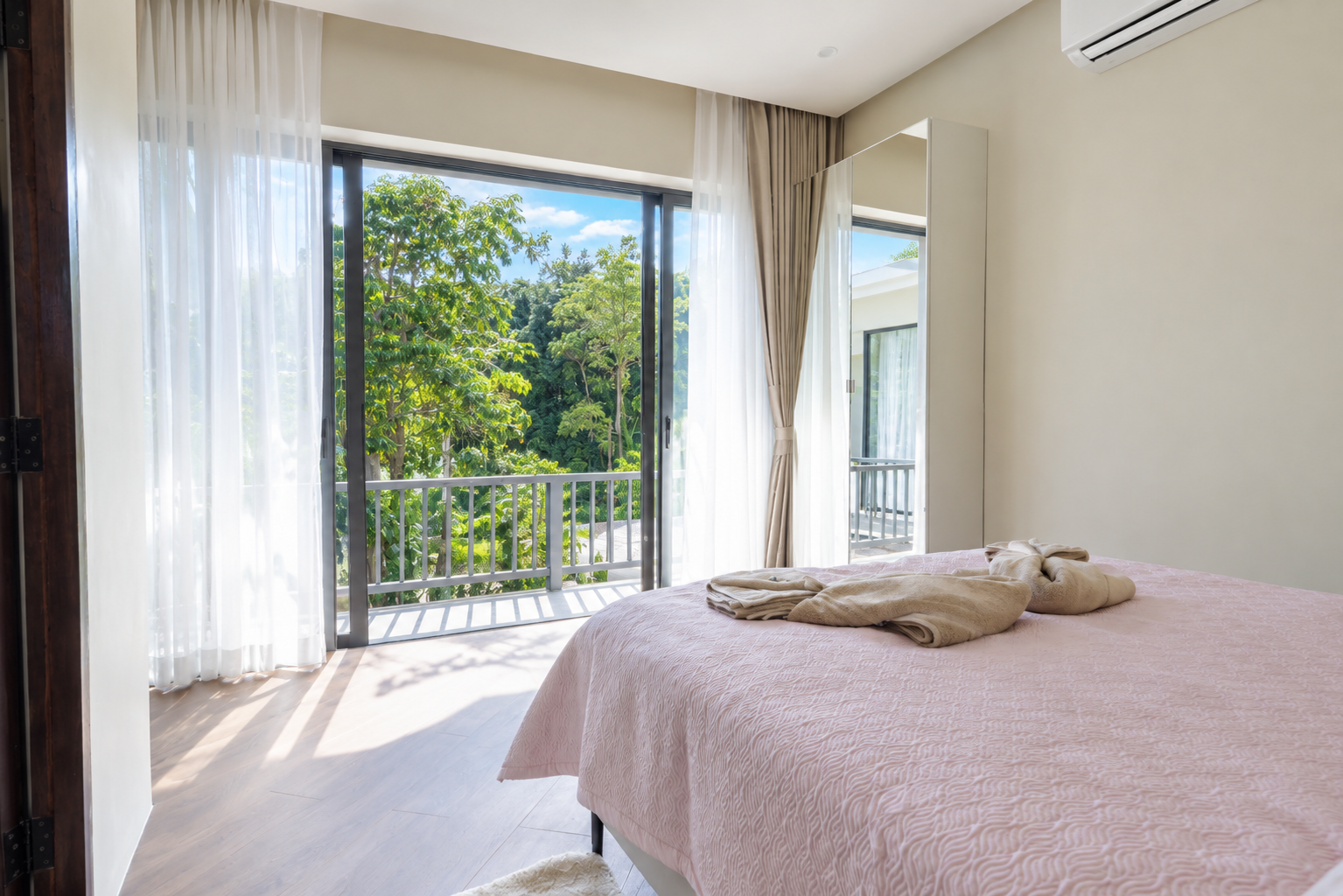 Bright bedroom with a double bed, full-length mirror and balcony overlooking the trees
